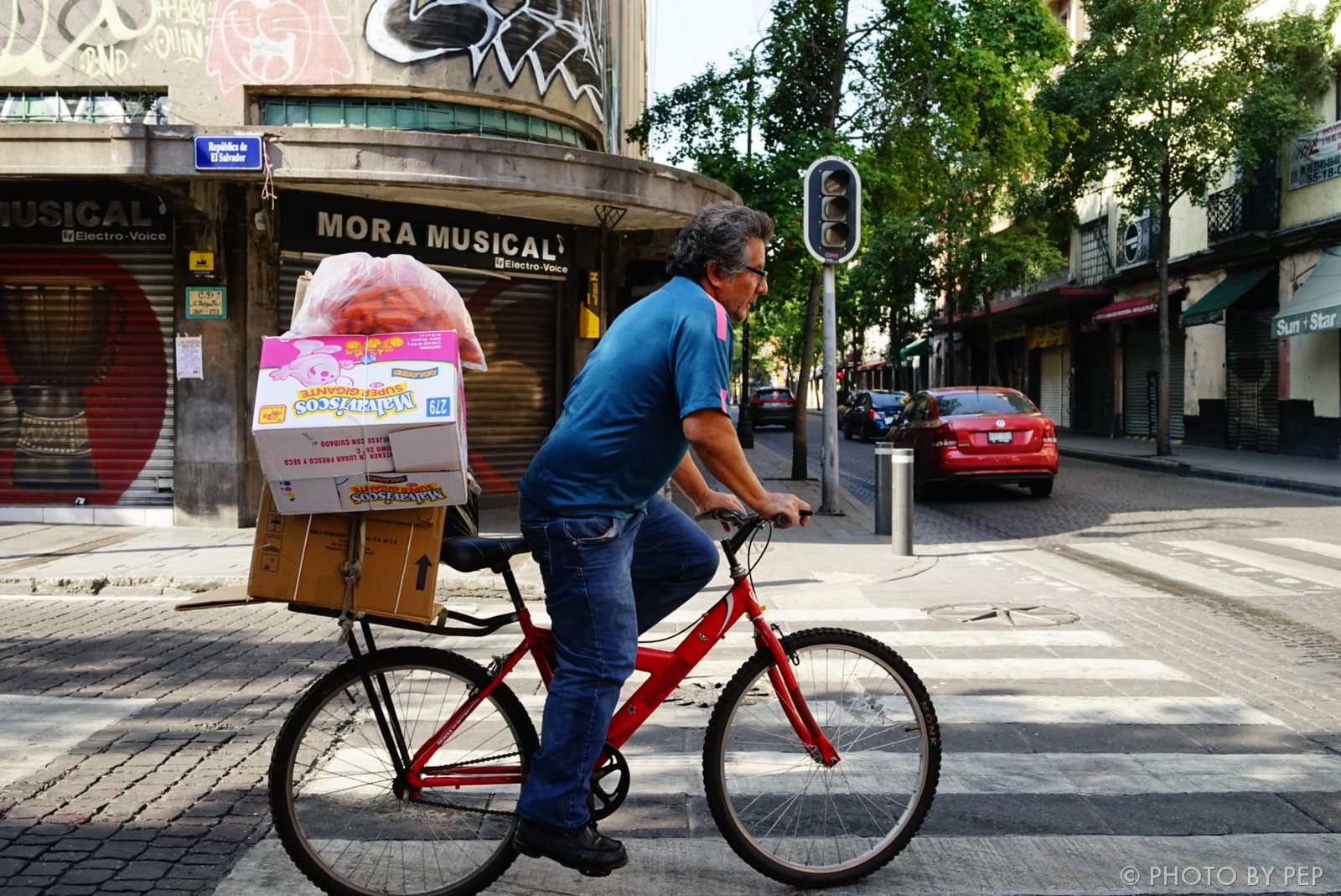 Vendor on a red bike loaded with boxes in Mexico City
